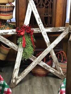 a wooden star is decorated with red bows and greenery in front of other baskets