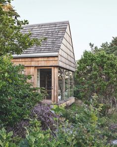 a small wooden building surrounded by trees and bushes