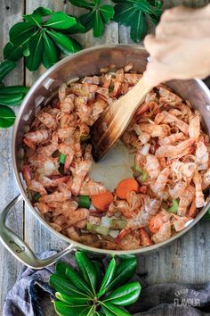 shrimp and carrots being cooked in a pot with a wooden spoon on the side