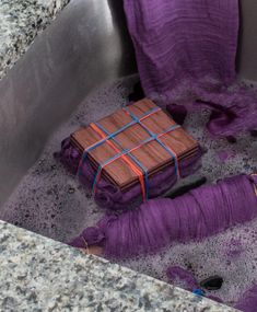 a purple object in a metal sink filled with water and stuff that looks like something out of space