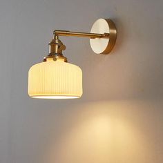 a wall light that is on the side of a wall next to a lamp shade