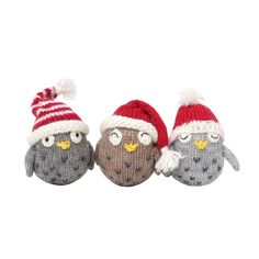 three knitted owls with hats on their heads are lined up against a white background