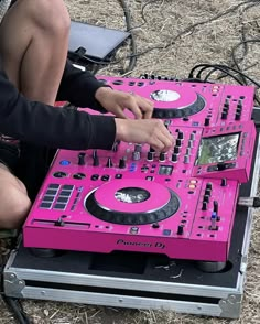 a person sitting on the ground with a pink dj's set up in front of them