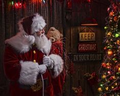 a santa clause holding a teddy bear in front of a christmas tree and other decorations