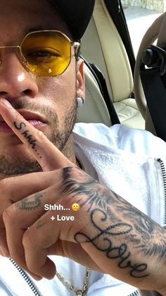 a man with tattoos on his arm making a peace sign while sitting in a car