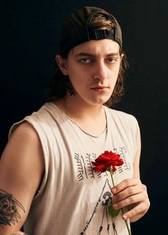 a young man holding a red rose in his right hand