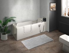 a white bath tub sitting next to a toilet in a bathroom on top of a hard wood floor