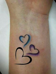 two hearts tattoo on the wrist with blue and black ink, one is in the shape of a heart