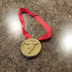 a medal with a red ribbon around it sitting on a counter top next to a pair of scissors