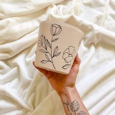 a woman's hand holding a cup with flowers painted on it