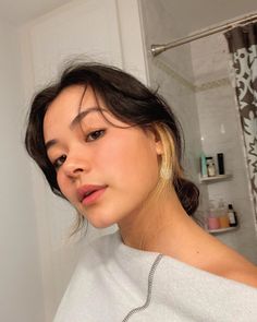 a woman in a white shirt is brushing her hair and looking at the camera with an intense look on her face