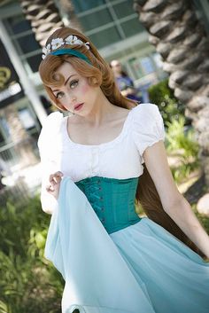 a woman in a blue and white dress is walking down the street wearing a tiara