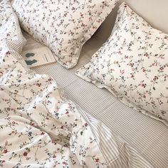 an unmade bed with floral sheets and pillows