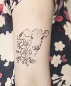 a woman's arm with a sheep and flowers tattoo on the left side of her arm