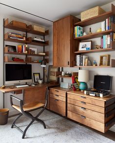 a desk with a computer on top of it next to a book shelf filled with books