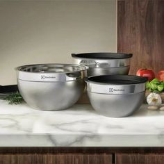 three stainless steel bowls sitting on top of a counter