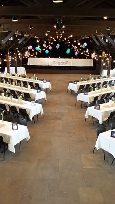 tables and chairs are set up in the center of an empty room with white tablecloths