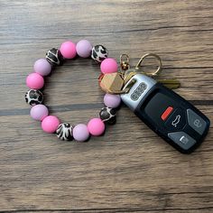 a pink and black beaded bracelet with a car key