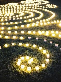 many lit candles are arranged on the grass