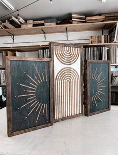 three wooden panels with designs on them in an office setting, against a backdrop of bookshelves