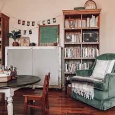 a green chair sitting in front of a wooden table next to a bookshelf