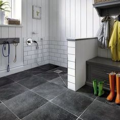 a bathroom with tiled floors and white walls, two coats hanging on the rack next to the shower