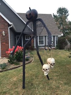 there is a fake spider with two skulls hanging from it's legs in the yard