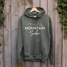 Grab this Mountain Seeker essentials hoodie to take with you on your next adventure or camping trip into nature!  Available in 6 colors choices! (Also available as a sweatshirt and t-shirt in shop.) ---- Production and Shipping ---- Production times are 2-7 business days All orders are received First Class (no UPS/FedEx) Shipping times may take an additional  3-5 days within the U.S. 5-10 days to Canada  *10-20 business days internationally ---- Apparel Info ---- We only use high quality shirts Green Hooded Hoodie For Outdoor, Hooded Sweatshirt With Kangaroo Pocket For Hiking, Hooded Sweatshirt With Kangaroo Pocket For Outdoor Activities, Green Sweatshirt With Kangaroo Pocket For Outdoor, Hooded Hoodie With Kangaroo Pocket For Hiking, Hooded Hoodie With Letter Print For Outdoor, Hoodie With Adjustable Hood For Outdoor Activities, Hooded Sweatshirt With Adjustable Hood For Outdoor Activities, Outdoor Hoodie With Kangaroo Pocket