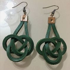 the earrings are made from green leather and have an interlocked design on them