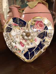 a teapot shaped like a heart with flowers and pearls on it's side