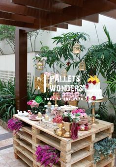 a wooden table topped with lots of food next to plants and potted planters