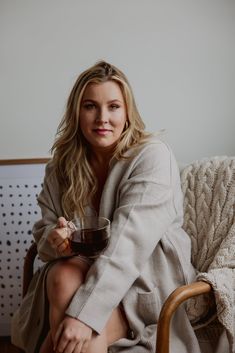 a woman sitting on a chair holding a glass of wine