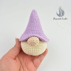 a crocheted doll with a purple hat on it's head is held up by a hand