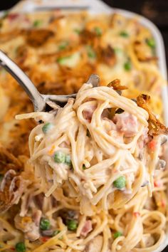 a fork full of pasta with meat and vegetables on it, in a casserole dish