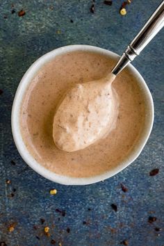 a spoon in a small bowl filled with some kind of sauce on top of a table