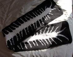 two black and white knitted socks laying on top of a bed next to each other