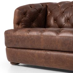 a brown leather couch sitting on top of a white floor