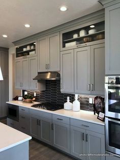 a kitchen with gray cabinets and white counter tops