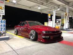 a red car is parked at a gas station