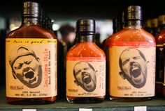 three bottles of hot sauce with an image of a man's face on them