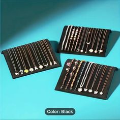 three black trays with different types of necklaces in them on a blue background