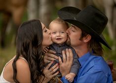 a man and woman kissing a baby while wearing a cowboy hat