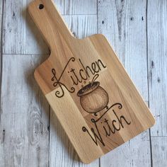 a wooden cutting board with the words kitchen witch on it