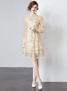 Majestic in its design, this tiered dress exudes a vintage charm that's perfect for the modern romantic. Crafted from layers of delicate, gossamer-like fabric, each tier is sprinkled with an array of floral embellishments that gleam subtly, reflecting the light with every movement. The high collar adds a touch of demure sophistication, while the full-length sleeves provide an elegant silhouette. This dress cinches at the waist, featuring a self-tie ribbon that allows for a customizable fit, enha Elegant Spring Tulle Lace Dress, Layered Spring Wedding Dress, Elegant Tiered Lace Wedding Dress, Spring Layered Dress For Party, Layered Spring Party Dress, Spring Layered Party Dresses, Elegant Lace Organza Dress For Spring, Elegant Mini Dress With Tiered Layered Hem, Elegant Mini Dress With Layered Tiered Skirt