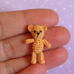 a tiny crocheted teddy bear sitting in someone's hand