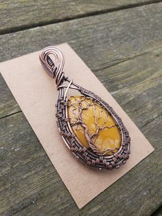 a wire wrapped pendant with an orange stone in the center on top of a piece of paper