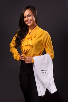 a woman is holding a white bag and smiling at the camera while standing in front of a black background