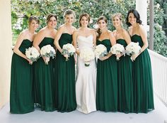 a group of women standing next to each other on a porch holding bouquets in their hands