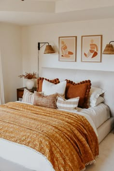 a bed with orange and white comforter in a bedroom next to two pictures on the wall