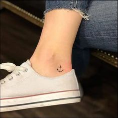 a small anchor tattoo on the foot of a woman's left ankle is shown